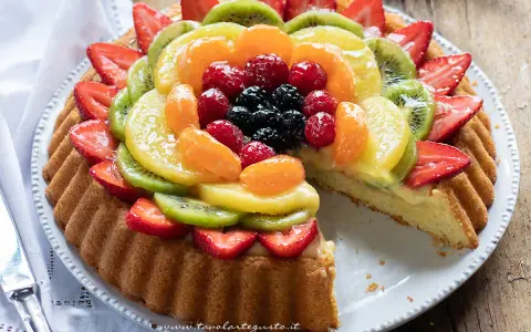Una deliziosa crostata morbida alla frutta, con fragole, kiwi, mandarini e frutti di bosco su una base soffice e crema.