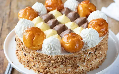 Torta Saint Honoré decorata con bignè caramellati, ciuffi di panna montata e crema pasticcera al cioccolato e vaniglia.