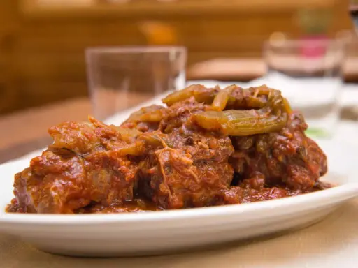 Un succulento piatto di coda alla vaccinara, cotta lentamente in un ricco sugo di pomodoro con verdure.
