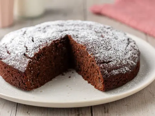 Una fetta è stata tolta da una torta al cioccolato morbida, cosparsa di zucchero a velo.