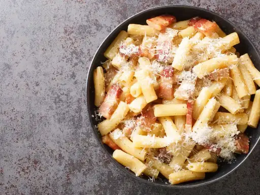 Un piatto di pasta alla gricia fumante, con guanciale croccante e abbondante pecorino romano.