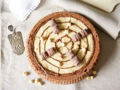 Torta Kinder Bueno con crema chiara, nocciole e decorazioni di cioccolato.