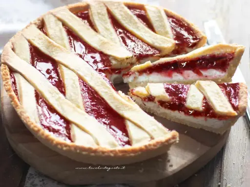 Una deliziosa crostata ricotta e marmellata, con fette tagliate che mostrano il ripieno cremoso e la crosta dorata.