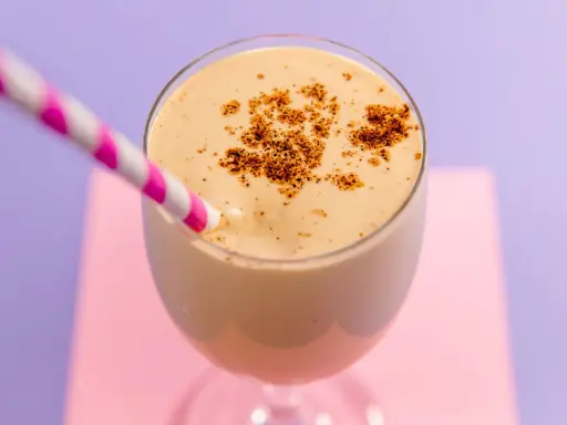 Delizioso spumone al caffè, guarnito con cacao in polvere, pronto da gustare con una cannuccia a righe rosa e bianche.