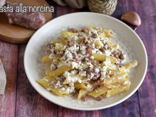 Piatto di pasta alla norcina con salsiccia sbriciolata e ricotta cremosa, un classico della cucina umbra.