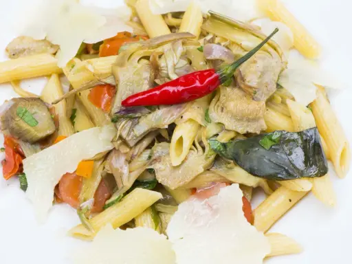 Penne con carciofi, pomodorini, peperoncino rosso e scaglie di parmigiano. Un piatto gustoso e colorato.