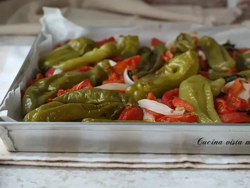 Friggitelli al forno con pomodori e cipolla, pronti per essere gustati.