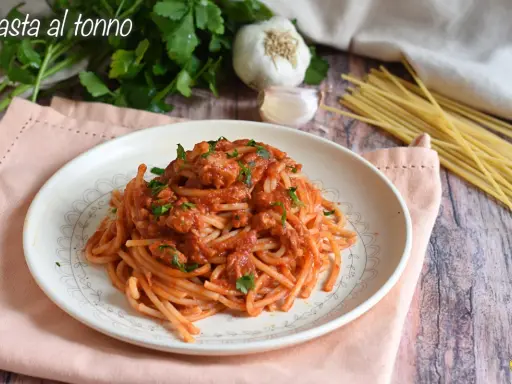 Piatto di spaghetti al sugo con tonno in scatola, guarnito con prezzemolo fresco. Ingredienti per un pasto veloce e gustoso.