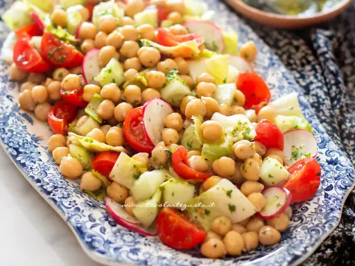 Un'appetitosa insalata di ceci con pomodorini, cetrioli e ravanelli, condita con erbe fresche.