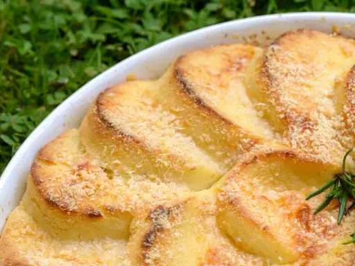 Gnocchi alla romana dorati e gratinati in una teglia bianca, con un rametto di rosmarino.