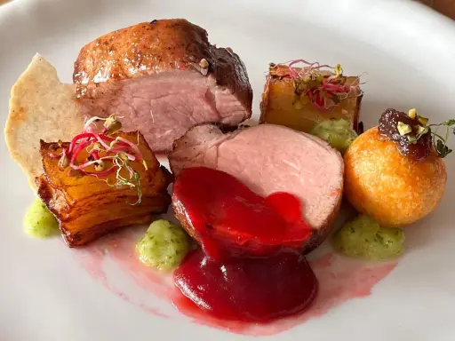 Piatto gourmet con filetto di maiale, patate croccanti, salsa rossa e guarnizioni verdi. Un'idea per le tue ricette di filetto di maiale.