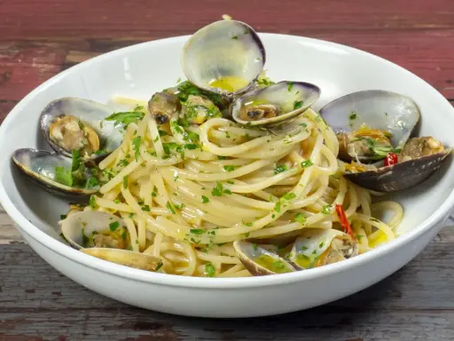 Spaghetti alle vongole surgelate, un piatto gustoso con pasta, vongole e prezzemolo.