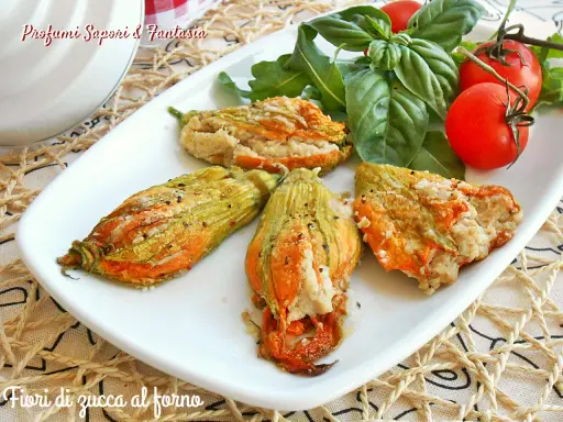 Deliziosi fiori di zucca al forno ripieni, serviti su un piatto bianco con pomodorini e basilico fresco.