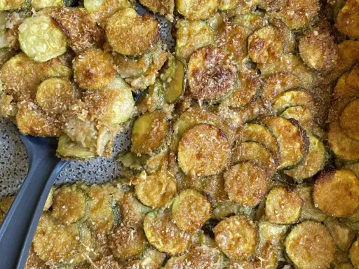 Fette di zucchine al forno dorate e croccanti, condite con parmigiano e pangrattato. Un contorno delizioso e facile da preparare.