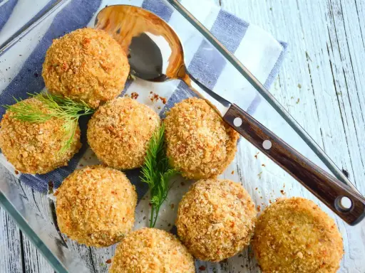 Polpette di merluzzo dorate e croccanti, guarnite con aneto fresco, pronte per essere servite.
