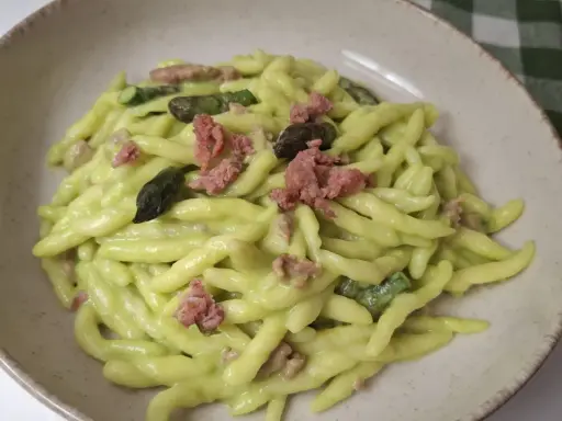 Piatto di pasta fresca con crema di asparagi, pezzetti di salsiccia e punte di asparagi.