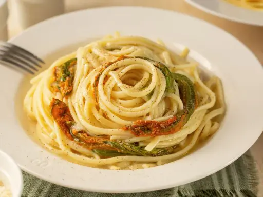 Un piatto di spaghetti conditi con delicati fiori di zucca, un classico della cucina italiana.