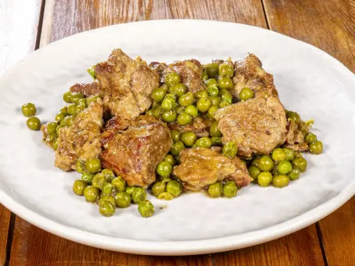 Un saporito agnello con piselli, un classico piatto italiano, servito su un piatto bianco.