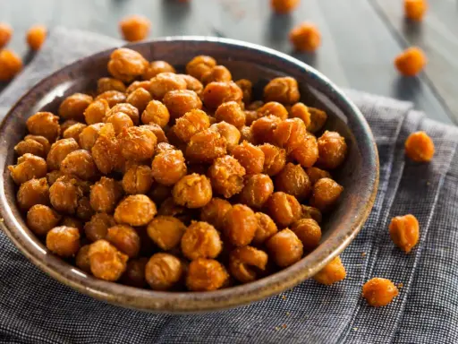 Ceci croccanti al forno, uno snack salutare e gustoso, serviti in una ciotola su un tovagliolo di lino.