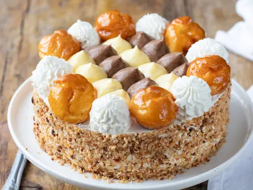 Torta Saint Honoré decorata con bignè caramellati, ciuffi di panna montata e crema pasticcera al cioccolato e vaniglia.