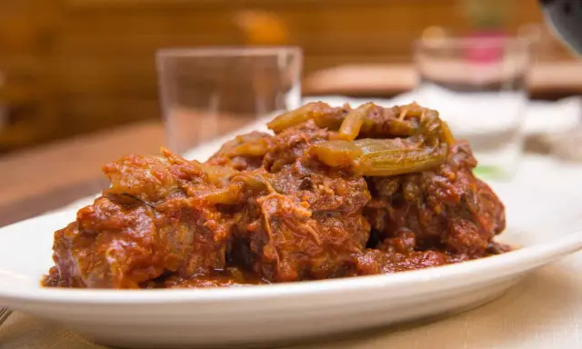 Un succulento piatto di coda alla vaccinara, cotta lentamente in un ricco sugo di pomodoro con verdure.