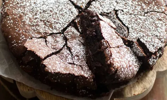 Una deliziosa torta al cioccolato fondente, con una crosta crepata e cosparsa di zucchero a velo, pronta per essere gustata.