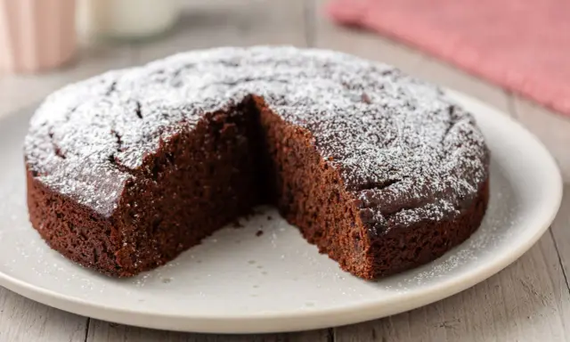 Una fetta è stata tolta da una torta al cioccolato morbida, cosparsa di zucchero a velo.