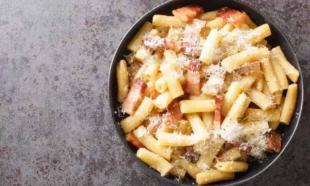 Un piatto di pasta alla gricia fumante, con guanciale croccante e abbondante pecorino romano.