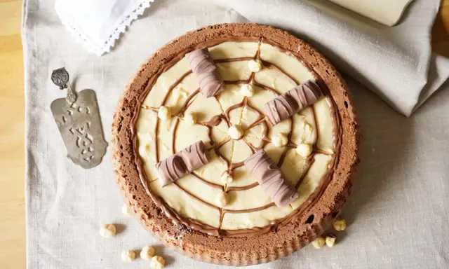 Torta Kinder Bueno con crema chiara, nocciole e decorazioni di cioccolato.