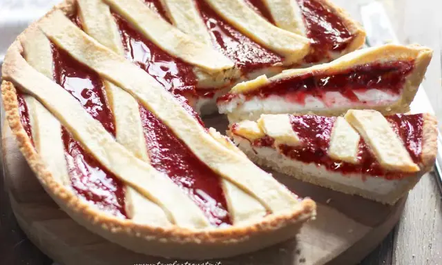Una deliziosa crostata ricotta e marmellata, con fette tagliate che mostrano il ripieno cremoso e la crosta dorata.
