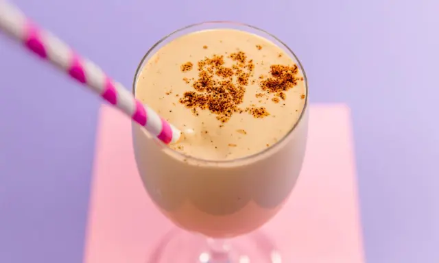 Delizioso spumone al caffè, guarnito con cacao in polvere, pronto da gustare con una cannuccia a righe rosa e bianche.