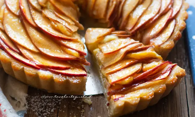 Una fetta di crostata di mele dorata, con mele caramellate disposte a rosa su una base friabile.