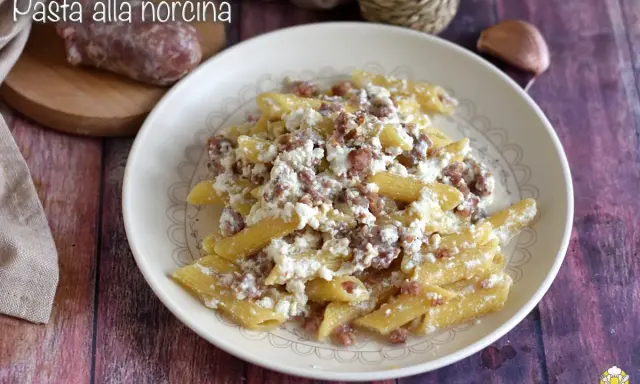 Piatto di pasta alla norcina con salsiccia sbriciolata e ricotta cremosa, un classico della cucina umbra.