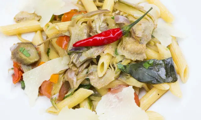 Penne con carciofi, pomodorini, peperoncino rosso e scaglie di parmigiano. Un piatto gustoso e colorato.