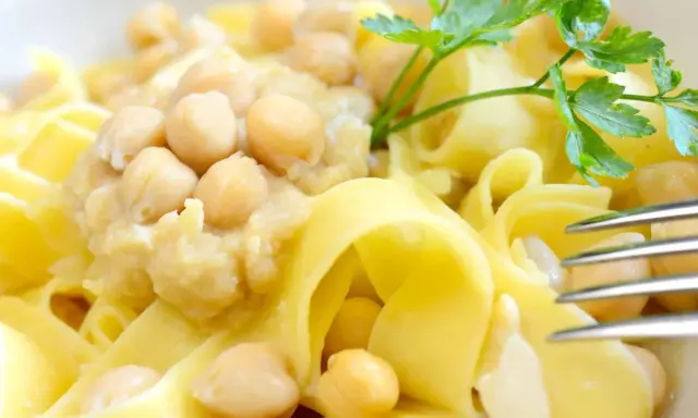 Piatto di ciceri e tria, pasta fresca con ceci cremosi e un rametto di prezzemolo.