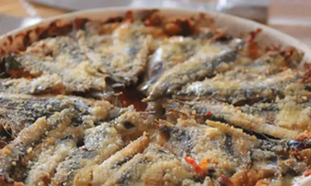 Tortino di alici cotto al forno, con panatura dorata e ingredienti saporiti.
