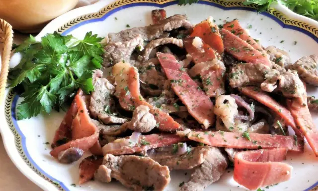 Straccetti di manzo con pancetta e cipolla, guarniti con prezzemolo fresco. Un piatto saporito e invitante.