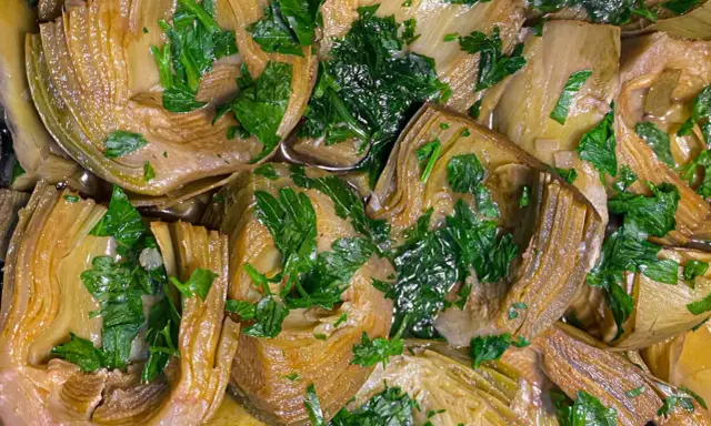 Deliziosi carciofi in padella, teneri e profumati, guarniti con prezzemolo fresco. Un piatto semplice e gustoso.