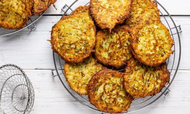 Un mucchio di rosti di zucchine dorati e croccanti su una griglia, pronti per essere gustati.
