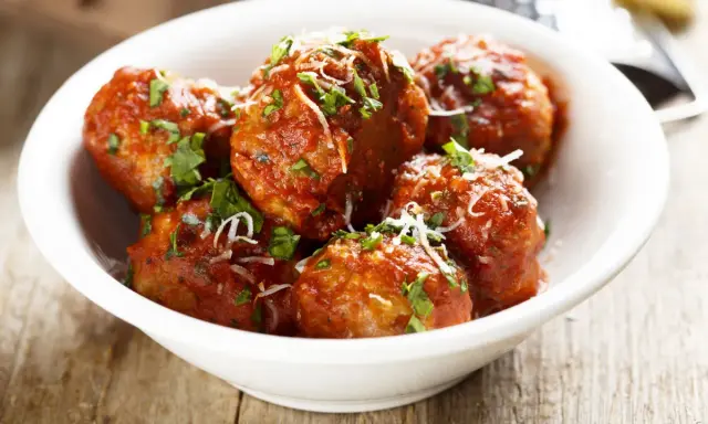 Polpette di carne morbide in salsa rossa, cosparse di parmigiano e prezzemolo fresco.