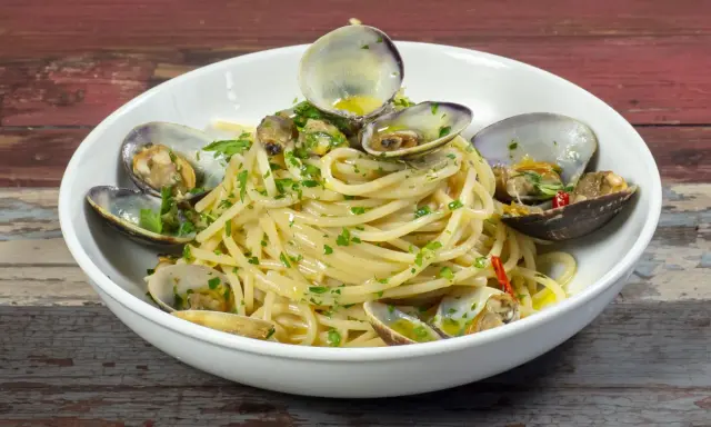 Spaghetti alle vongole surgelate, un piatto gustoso con pasta, vongole e prezzemolo.