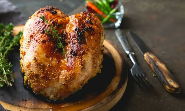 Petto di pollo al forno dorato e succulento, condito con senape e erbe aromatiche, pronto per essere gustato.