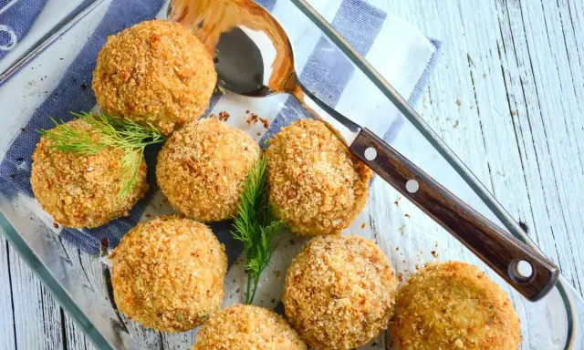 Polpette di merluzzo dorate e croccanti, guarnite con aneto fresco, pronte per essere servite.