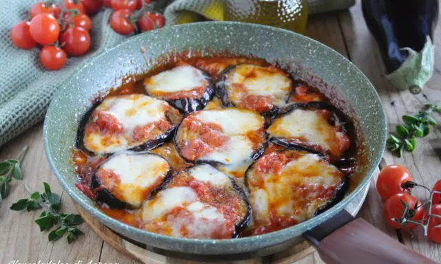 Melanzane alla pizzaiola in padella, con pomodoro e mozzarella filante, contornate da pomodorini freschi e basilico.