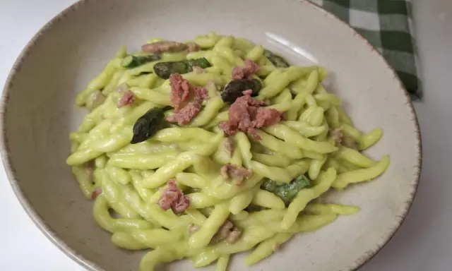Piatto di pasta fresca con crema di asparagi, pezzetti di salsiccia e punte di asparagi.