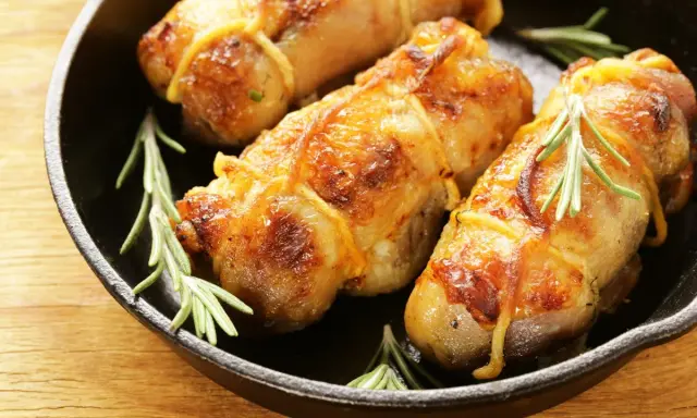 Involtini di pollo in padella, dorati e succulenti, con rametti di rosmarino fresco.