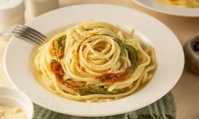 Un piatto di spaghetti conditi con delicati fiori di zucca, un classico della cucina italiana.