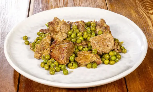 Un saporito agnello con piselli, un classico piatto italiano, servito su un piatto bianco.