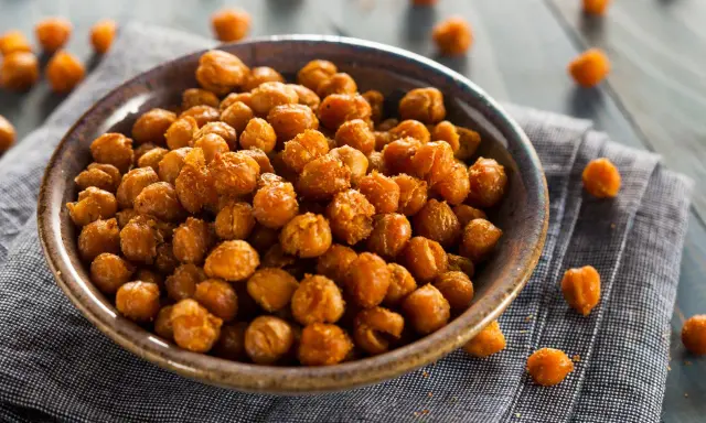 Ceci croccanti al forno, uno snack salutare e gustoso, serviti in una ciotola su un tovagliolo di lino.