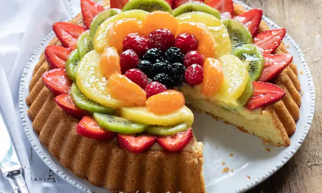 Una deliziosa crostata morbida alla frutta, con fragole, kiwi, mandarini e frutti di bosco su una base soffice e crema.